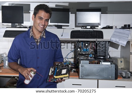Small business: computer technician with motherboard at workshop