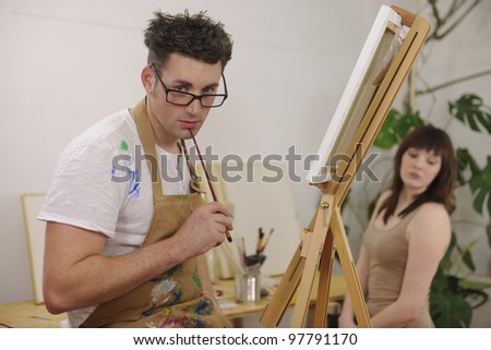 male artist painting female model at art studio
