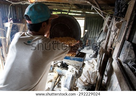 FALAM, MYANMAR - JUNE 17 2015: Making pig feed using a grinding machine in the town of Falam in Chin State, Myanmar.