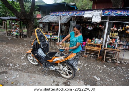 CHIN STATE, MYANMAR - JUNE 16 2015: Lady refills gasoline from a bottle in the recently opened to foreigners area of Chin State - western Myanmar (Burma)