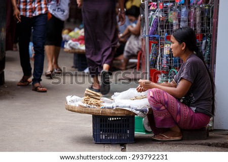YANGON, MYANMAR - JUNE 12 2015: Woman selling small dried fish on one of the hottest recorded days before monsoon season in Yangon, Myanmar.