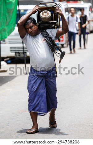YANGON, MYANMAR - JUNE 12 2015: Man carrying heavy load on one of the hottest recorded days before monsoon season in Yangon, Myanmar.