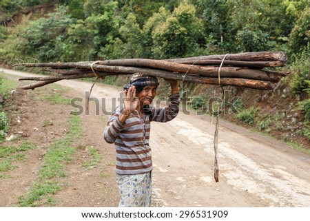 FALAM, MYANMAR - JUNE 17 2015: Local woman carries wood on her head in the recently opened to foreigners area of Chin State - western Myanmar (Burma)