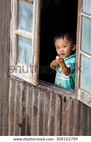 CHIN STATE, MYANMAR - JUNE 18 2015: Cute young boy in window in the recently opened for tourists Chin State Mountainous Region, Myanmar (Burma)