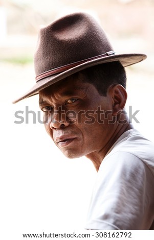 CHIN STATE, MYANMAR - JUNE 18 2015: Smart man in hat, sitting in the recently opened for tourists Chin State Mountainous Region, Myanmar (Burma)