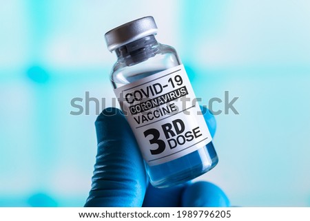 doctor with Coronavirus vaccine bottle with the name of the Third vaccine on the label. COVID-19 Vaccine Vial for vaccination tagged with 3rd dose