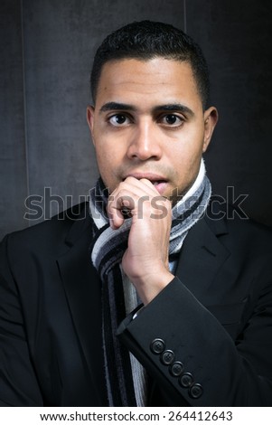 man young executive with hand on her mouth and a look of doubt in front of a gray wall / Young businessman with expression of confusion