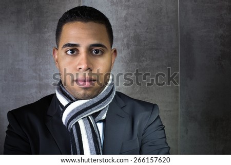 portrait of elegant young latin man wearing a suit and scarf in background grey wall / portrait business man waiting beside the wall