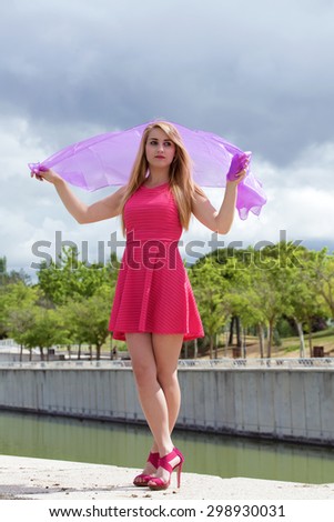 portrait of beautiful girl posing with flying pink scarf / pensive woman with pink scarf in field