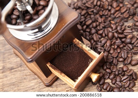 Vintage coffee bean grinder and fresh ground coffee on wooden top next coffee beans