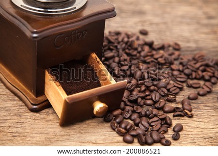 Vintage coffee bean grinder and fresh ground coffee on wooden top next coffee beans
