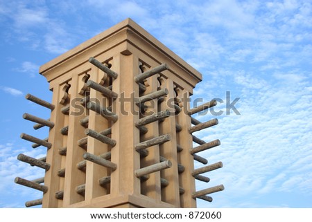 an arabic wind tower against a cloudy sky