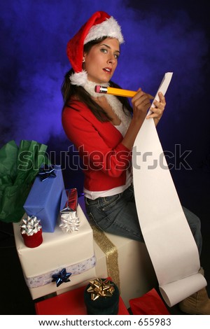 girl in santa hat is checking her list for the holidays surrounded by gifts in a misty blue background