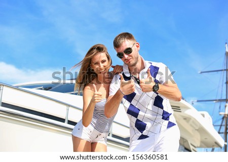 Happy couple standing on the pier in the background of the yacht