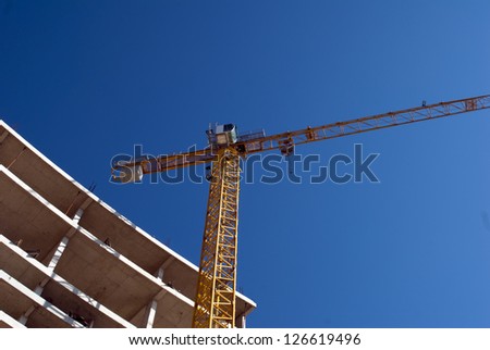 Reinforced steel & concrete building under construction. Safety guard rails, flyforms and tower crane