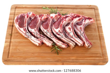 lamb chops on a cutting board in front of white background
