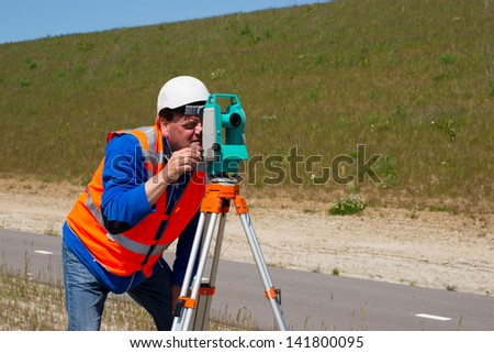 Engineer working with a modern theodolite or total station on a tripod