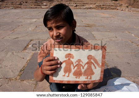ORCHHA, INDIA - DEC 23: An unidentified indian boy shows his original naive drawing of the happy family on December 23 2012 in Orchha, Madhya Pradesh, India. The state\'s literacy rate figures 64.11%.