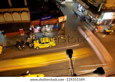KOLKATA, INDIA - JAN 13: Night city with fast moving cars and Ambassador taxi cabs on January 13 2013 in Kolkata, India. Hindustan Ambassador is a car manufact. by Hindustan Motors of India since 1958