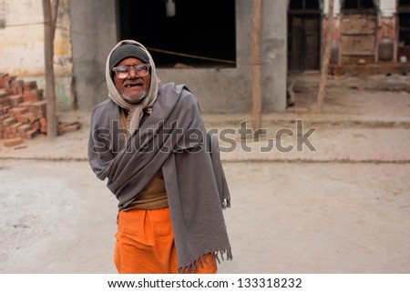 UTTAR PRADESH, INDIA - JAN 27: Poor senior man in glasses with no teeth goes on the street on January 27, 2013 in Ayodhya, India. 60-plus age group in India will increase to 100 million people in 2013