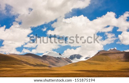 Mountain range on a sunny day is covered with clean white clouds
