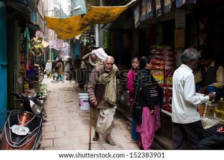VARANASI, INDIA - JAN 1: Elderly man is leaning on a cane on a street of the oldest Indian city on January 1, 2013. The city produces 350 million litres per day of sewerage & 425 tonnes of solid waste