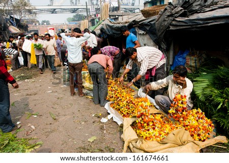KOLKATA, INDIA - JAN 13: Male flower sellers prepare the goods on the famous marketp on January 13, 2012 in Kolkata. Only 0.81% of the Kolkata\'s workforce employed in the primary sector (agriculture)