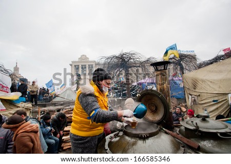 KYIV, UKRAINE - DEC 8: Girl pours hot tea from a huge barrel of the street kitchen on the crowded Maidan square during two weeks anti-government protest on December 8, 2013, in Kiev, Ukraine.