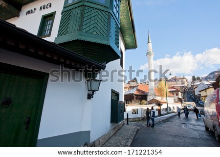 SARAJEVO, BOSNIA AND HERZEGOVINA - DEC 25: People and cars move on the narrow street with mosque and old Ottoman style house on December 25 2013 in Sarajevo. Population of the city is about 420,000.