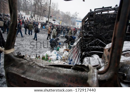 KIEV, UKRAINE - JAN 21: Many active people walk around the winter snowy street with burned cars and buses during anti-government protest Euromaidan on January 21, 2014, in center of Kyiv, Ukraine
