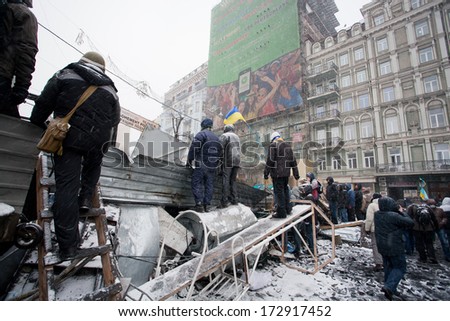 KIEV, UKRAINE - JAN 21: Men wait for attack and watch out police squad behind the barricades with metal scrap during anti-government protest Euromaidan on winter street on January 21, 2014, in Kiyv