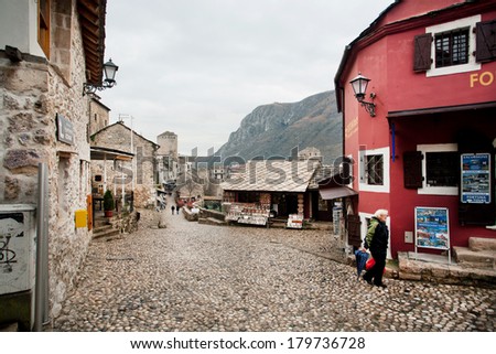 MOSTAR, BOSNIA AND HERZEGOVINA - DEC 28: Elderly lady walk through touristic street of the ancient Balkan city on December 28, 2013. Old Mostar is inscribed on World Heritage List by UNESCO in 2005