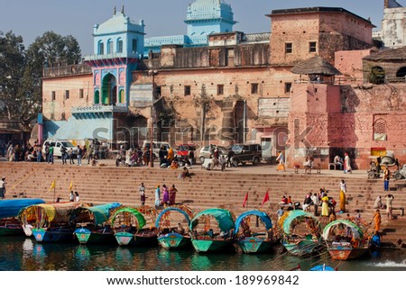 MADHYA PRADESH, INDIA - DEC 27: Many riverboats dock at the pier riverbank near the old indian city wall of red color on December 27, 2012 in Chitracoot. Population of Chitrakoot is 22,294 people.