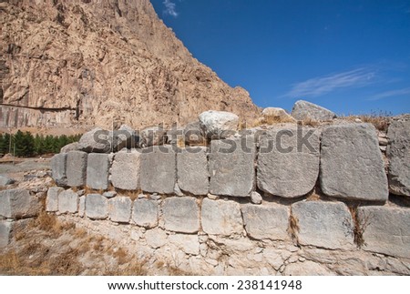 Masonry walls destroyed in the valley of the Middle East against the high rocky mountains on background.