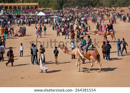 JAISALMER, INDIA - MAR 1: People in the crowd have fun with camels on the outdoor party during the rural Desert Festival on March 1, 2015. Every winter Jaisalmer takes the famous Desert Festival