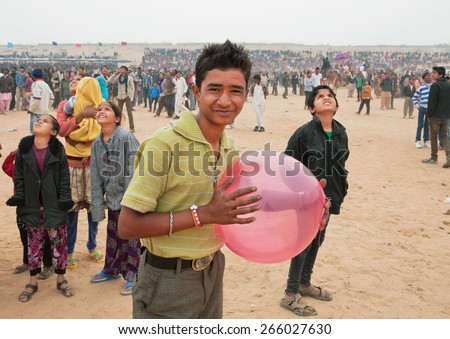 JAISALMER, INDIA - MAR 1: Happy young man with balloon walking in the crowd of people during the Desert Festival on March 1, 2015 in Rajasthan. Every winter Jaisalmer takes the famous Desert Festival