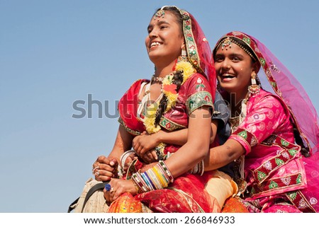 JAISALMER, INDIA - MAR 1: Happy faces of village women in red dresses drive the camel during the rural Desert Festival on March 1, 2015. Every winter Jaisalmer takes the famous Desert Festival
