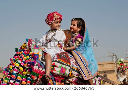 JAISALMER, INDIA - MAR 1: Unidentified boy and girl driving the camel with happy faces during carnival of the traditional Desert Festival on March 1 2015. Every winter Jaisalmer takes Desert Festival