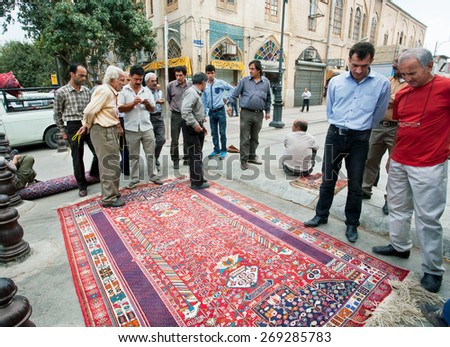 SHIRAZ, IRAN - OCT 21: Crowd of men talking about ancient carpet near the Persian rugs market on October 21, 2014. With population of 1,500,000, Shiraz is one of the oldest cities of ancient Persia.