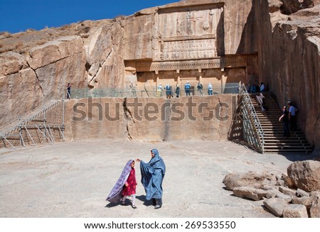 PERSEPOLIS, IRAN - OCT 22: Unidentified girls play next to the historical tomb of persian king Artaxerxes III on October 22, 2014. UNESCO declared citadel of Persepolis a World Heritage Site in 1979