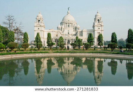 KOLKATA, INDIA - JAN 16: People walk past the facade of famous Victoria Memorial near the lake on January 16, 2013. The garden of the Victoria Memorial was designed on area of 0.26 sq.km