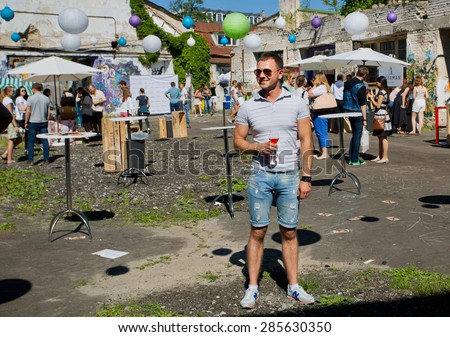 KYIV, UKRAINE - JUNE 6, 2015: Young man with glass of wine drinking alone during outdoor Kiev Food & Wine Festival on June 20, 2014. Kiev is the 8th largest city in Europe with populat. of 2,900,000