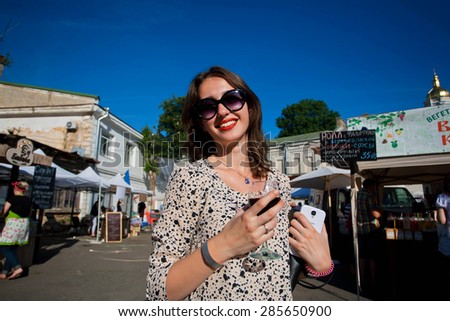KYIV, UKRAINE - JUNE 6, 2015: Beautiful lady in sunglasses smiling and drinking wine during the Kiev Food & Wine Festival on June 20, 2014. Ukrainian capital, Kiev has population near 2,900,200