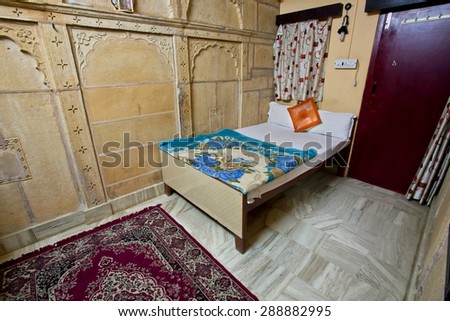 JAISALMER, INDIA - MAR 1: Interior of a cheep single room with a bed and carpet in a guest house on March 1, 2015. Jaisalmer lies in the heart of the Thar Desert and has a population of about 78,000.