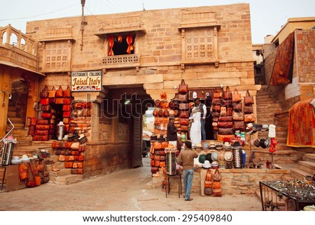 JAISALMER, INDIA - FEB 2: Traders of camel leather stores waiting for customers on indian street with brick houses on February 2, 2015. Every winter Jaisalmer takes Desert Festival of Rajasthan
