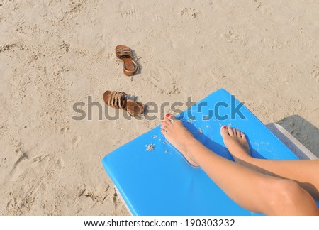 bare feet on deck chair chilling at the beach