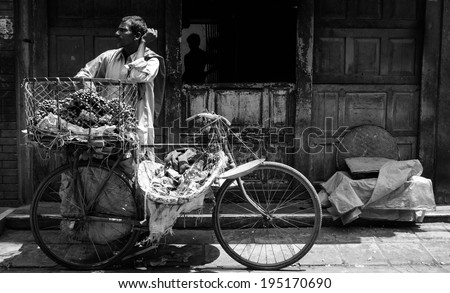 April 16, 2010 Kathmandu, Nepal. A fruit Merchant with his bicycle basket full of fruit waiting for a customer to buy. Black and White photo makes it more dramatic.