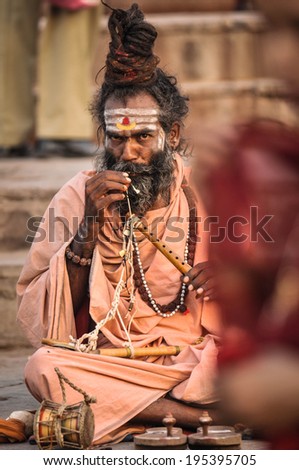 Varanasi, India - April 19, 2010: Happy Guru getting ready to play flute at Ganga river. The most holy river of India and Hindu culture.
