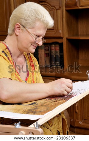 Woman embroidering a picture (cross stitch)