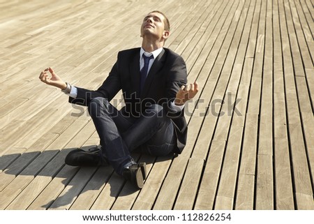Young businessman in the position of the lotus. Man sitting at floor in a relaxation position